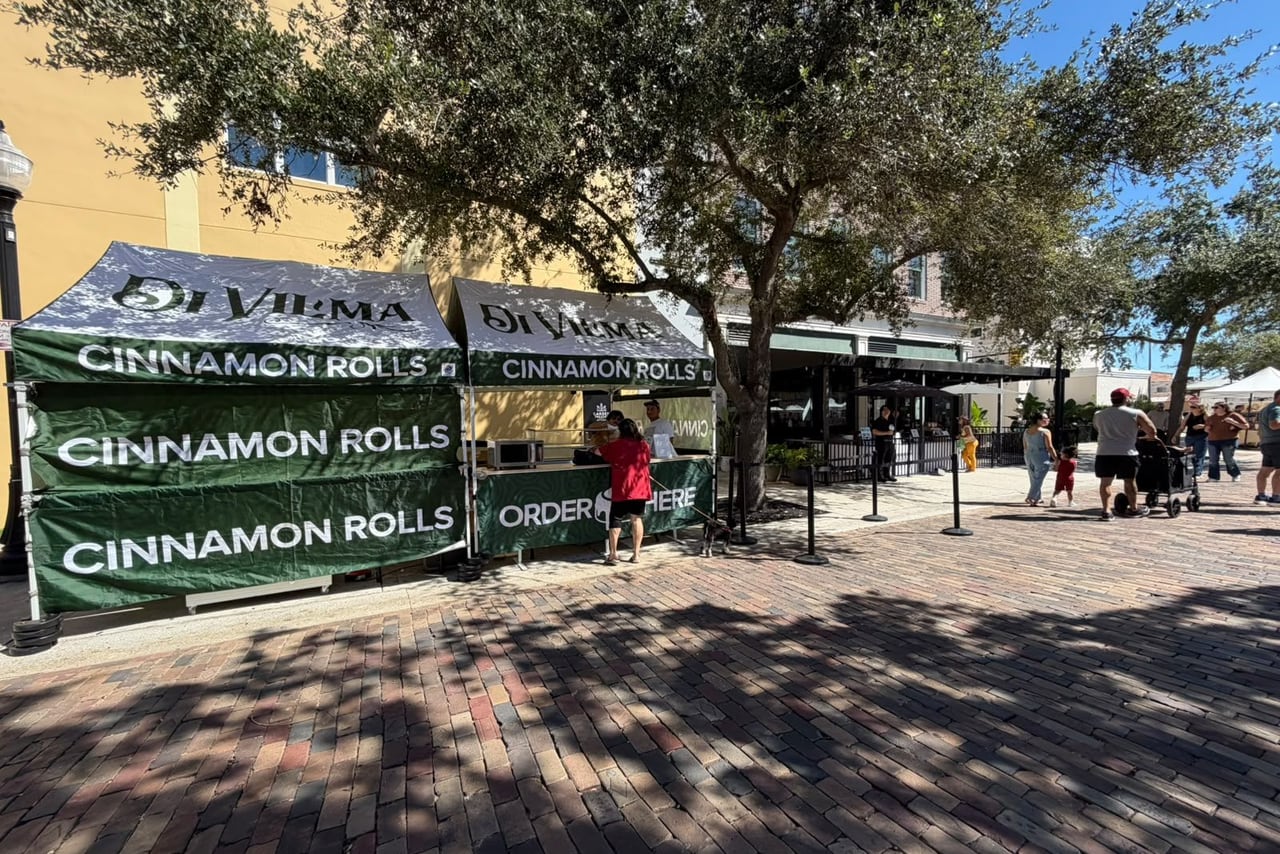 Barraca de cinnamon roll com toldo verde, na feira de sábado