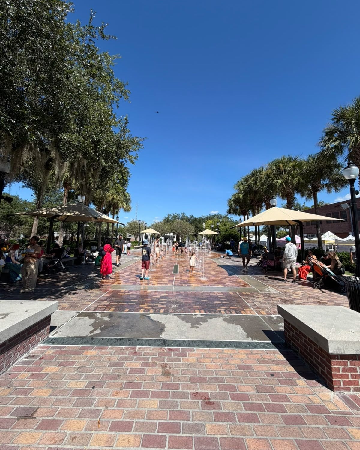 Praça do centro de Winter Garden com fonte de chão, guarda-sóis e palmeiras